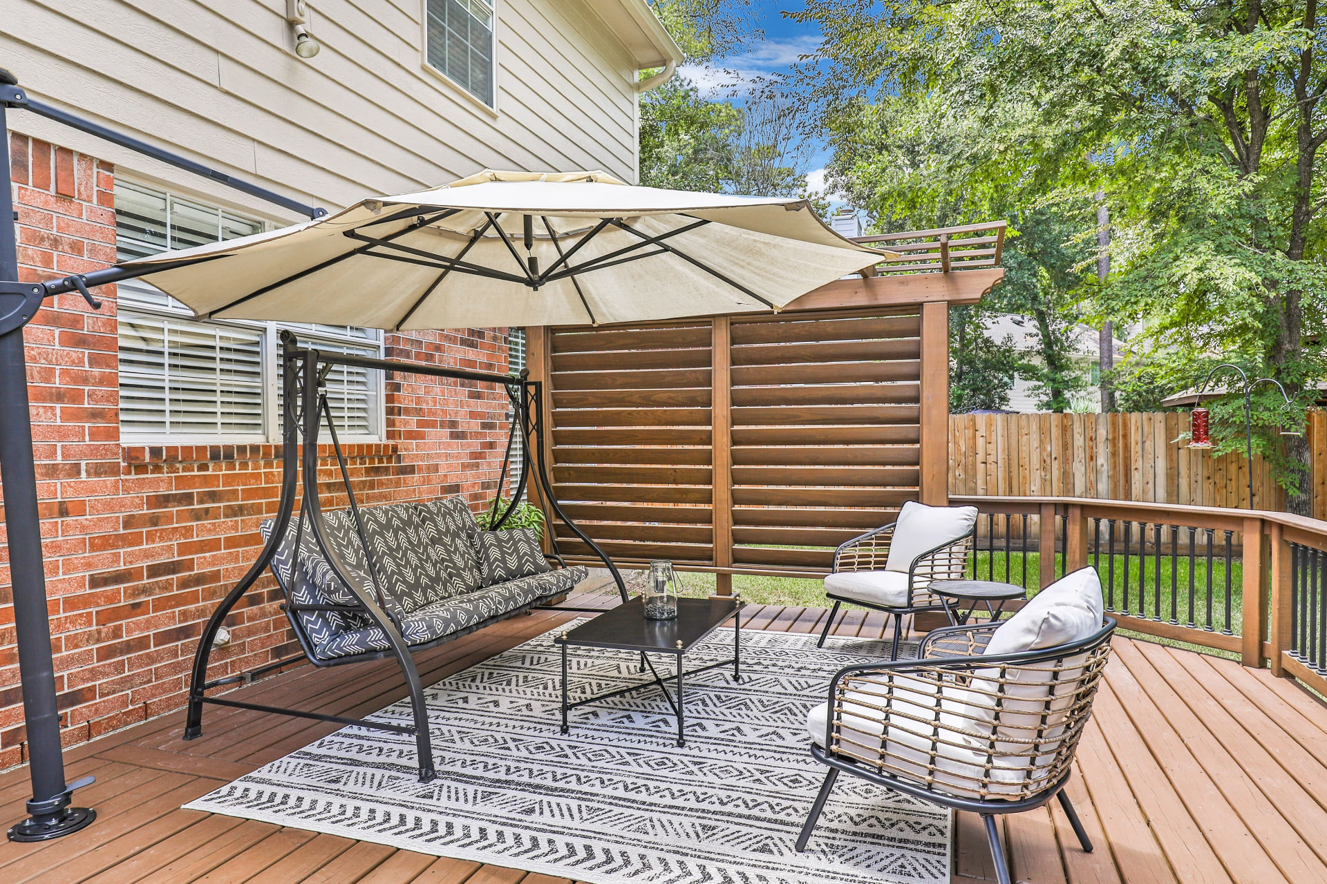 Curved wood deck with swing, cantilever umbrella and stained pergola privacy screen
