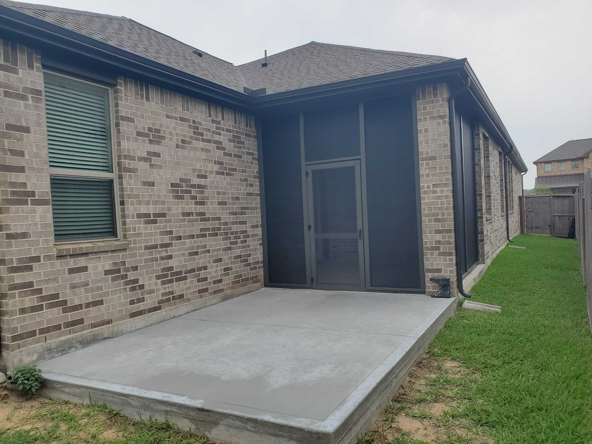 Screened porch enclosure with dark mesh panels and screen door on a brick home
