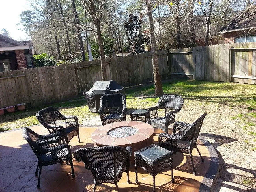 Round gas fire pit with fire glass on a stamped concrete patio with wicker seating