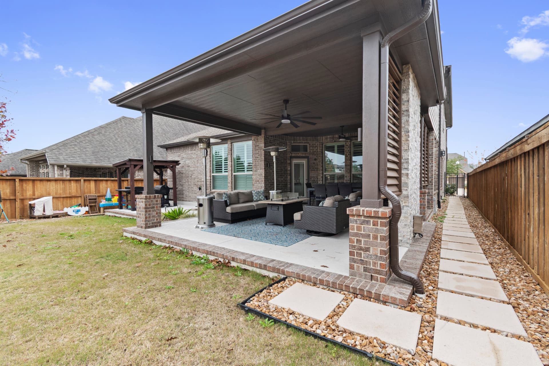 Attached patio cover with brick columns and lounge with fire table