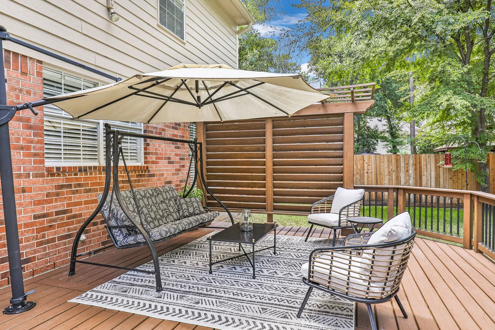 Curved wood deck with swing, cantilever umbrella and stained pergola privacy screen