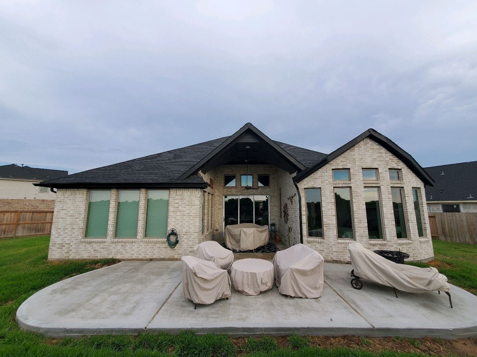 Rear elevation of brick home with new stamped concrete patio ready for outdoor living build