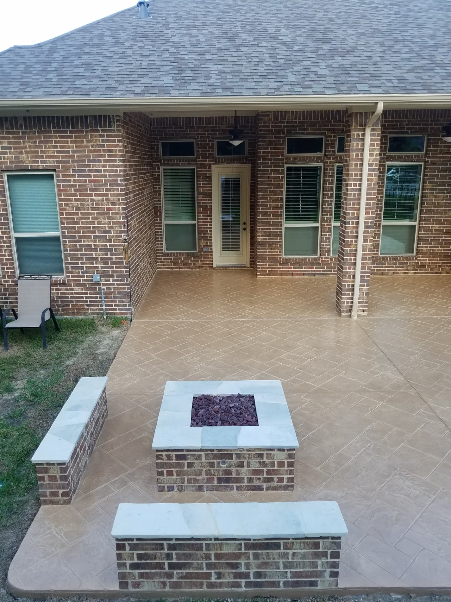 Square brick natural gas fire pit with matching seat walls on a stamped patio