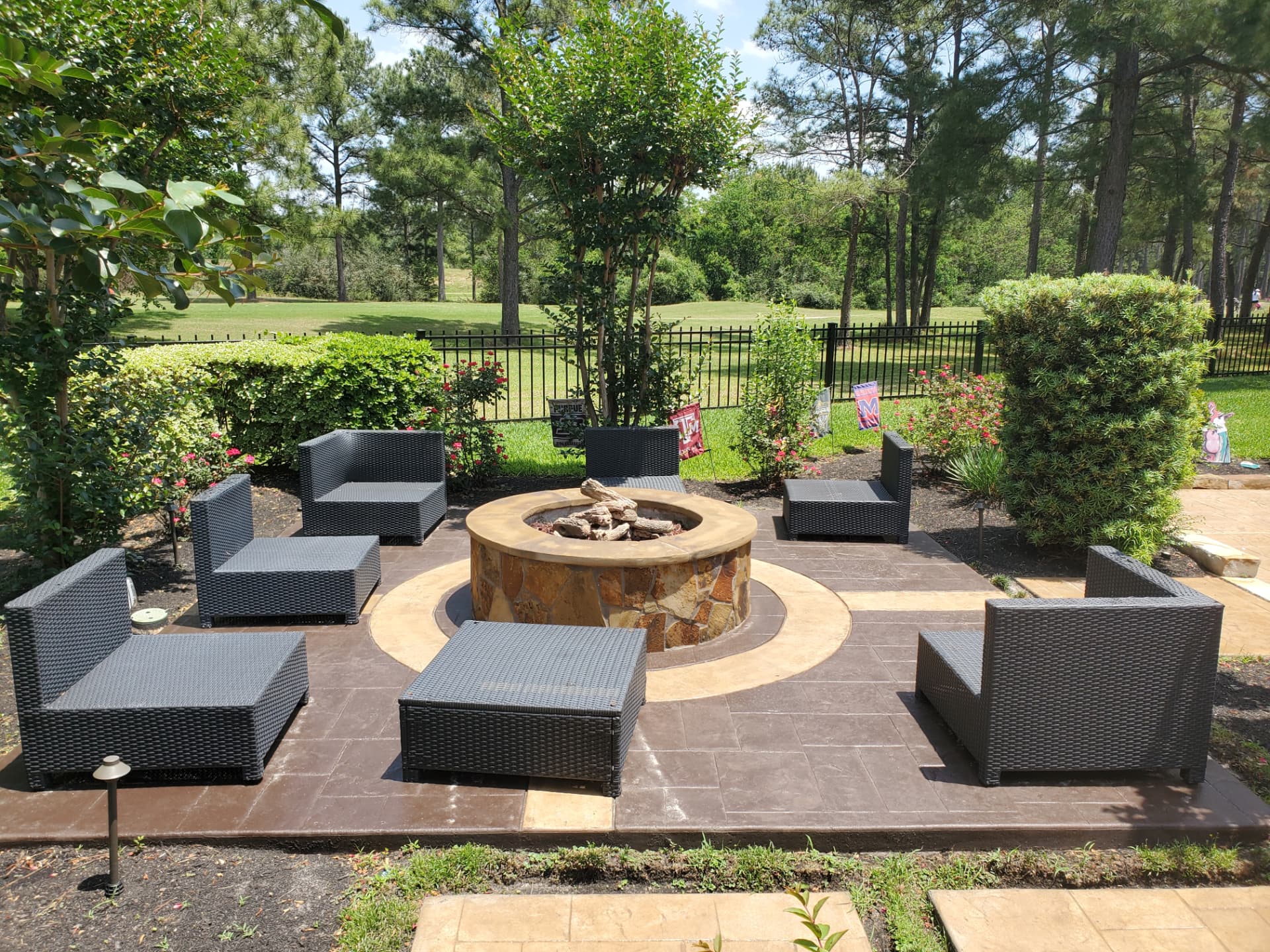 Stone gas fire pit on a stamped concrete patio with lounge seating overlooking a golf course