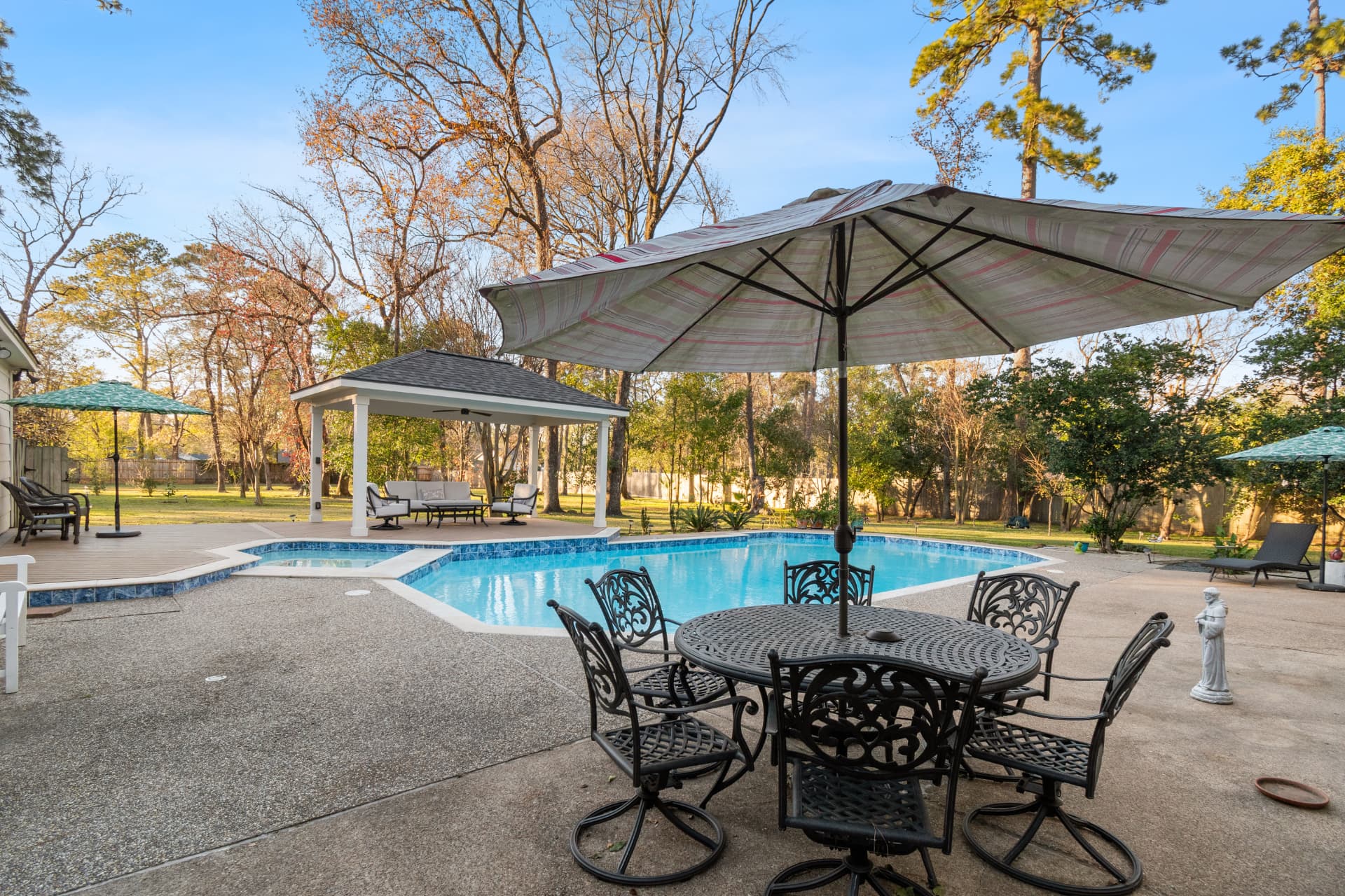 Backyard swimming pool with detached pavilion and travertine patio