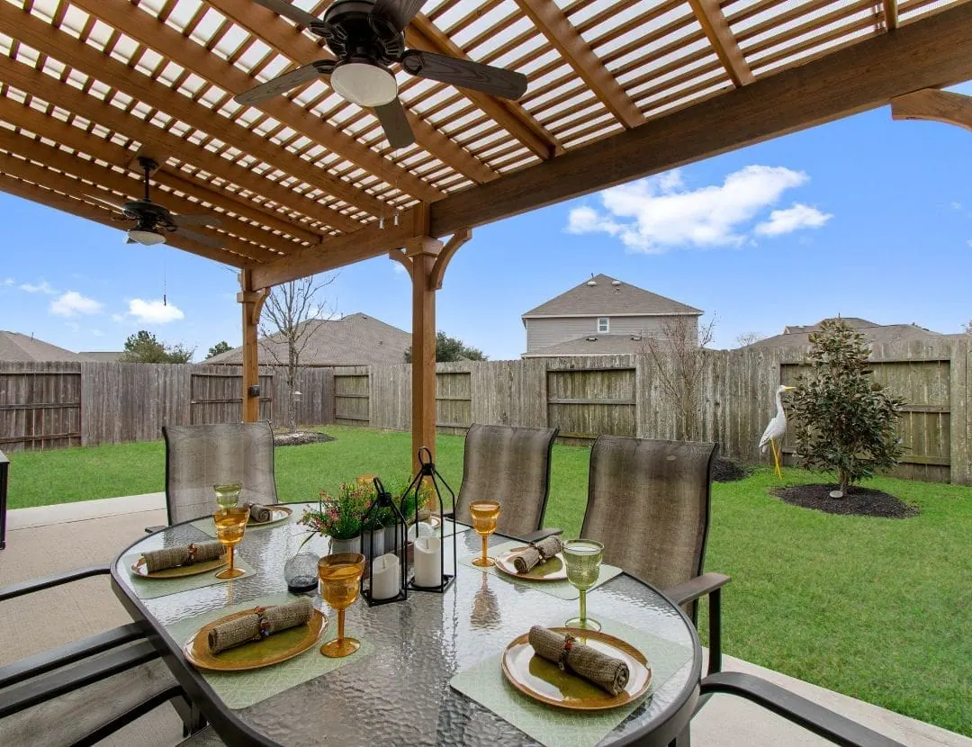 Attached cedar pergola with lattice roof and ceiling fans over patio dining