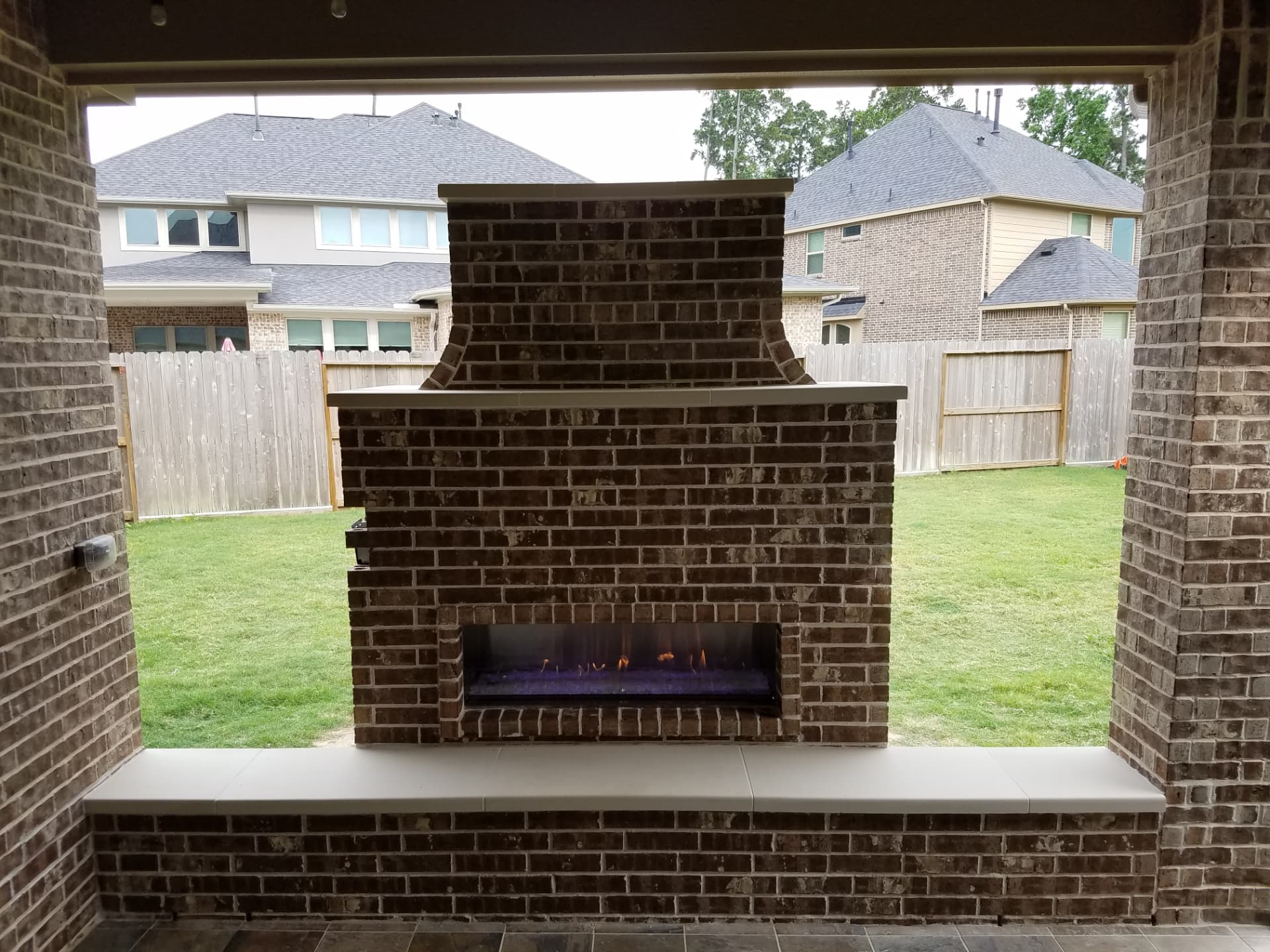 Brick outdoor fireplace with a linear gas burner and full-width hearth bench