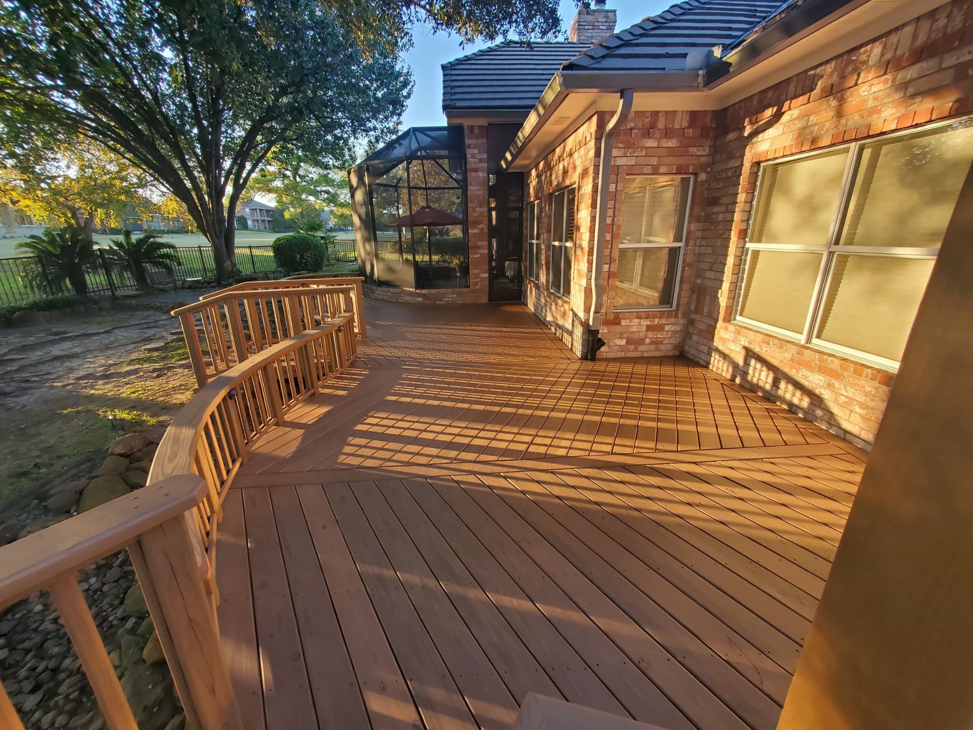 Curved wood deck with railing wrapping around brick home on golf course