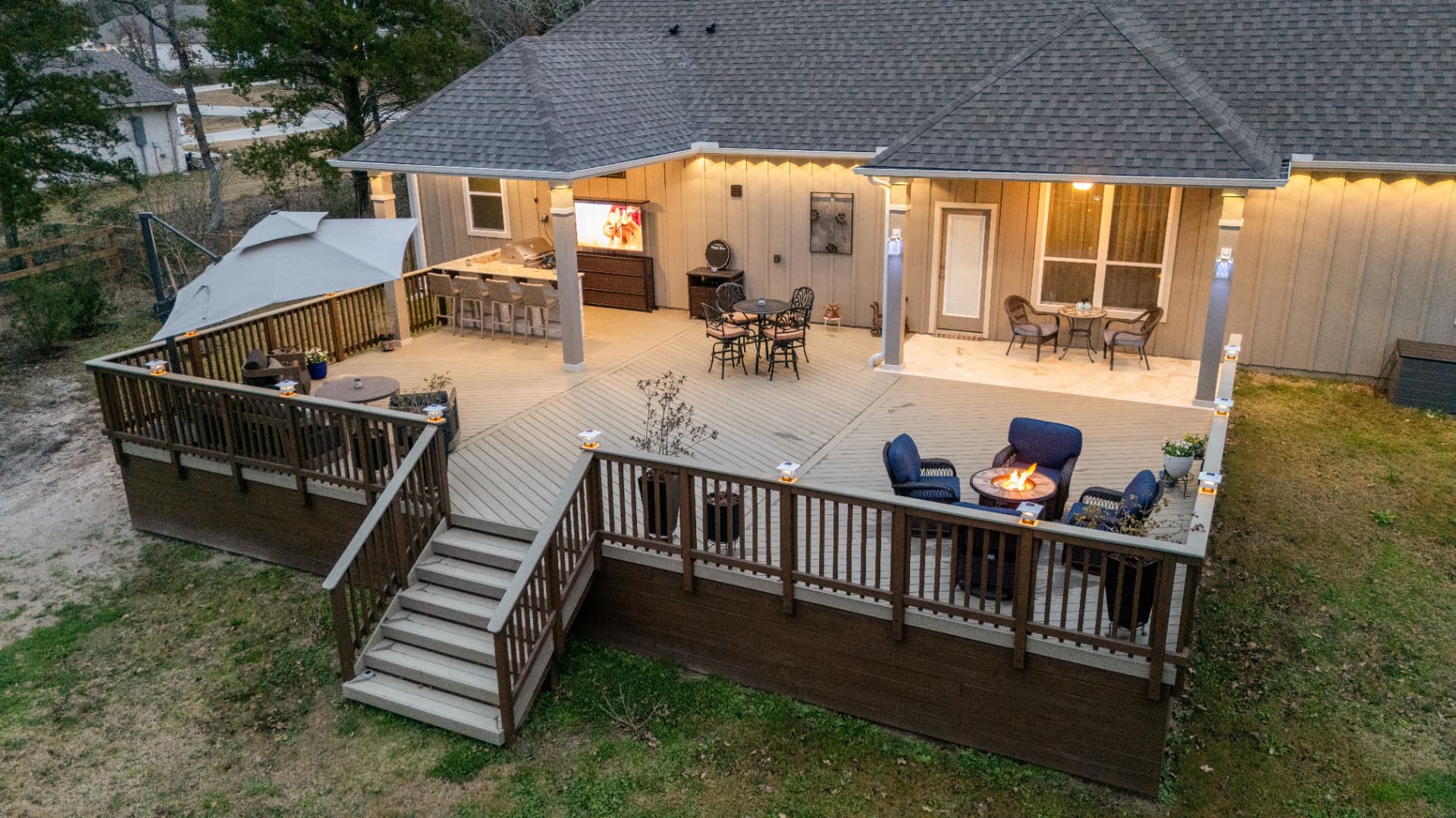 Aerial view of expansive multi-level deck with covered outdoor kitchen and fire pit