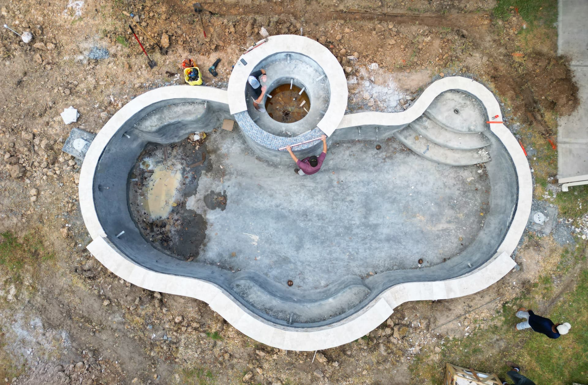 Aerial view of custom pool construction with raised spa and travertine coping