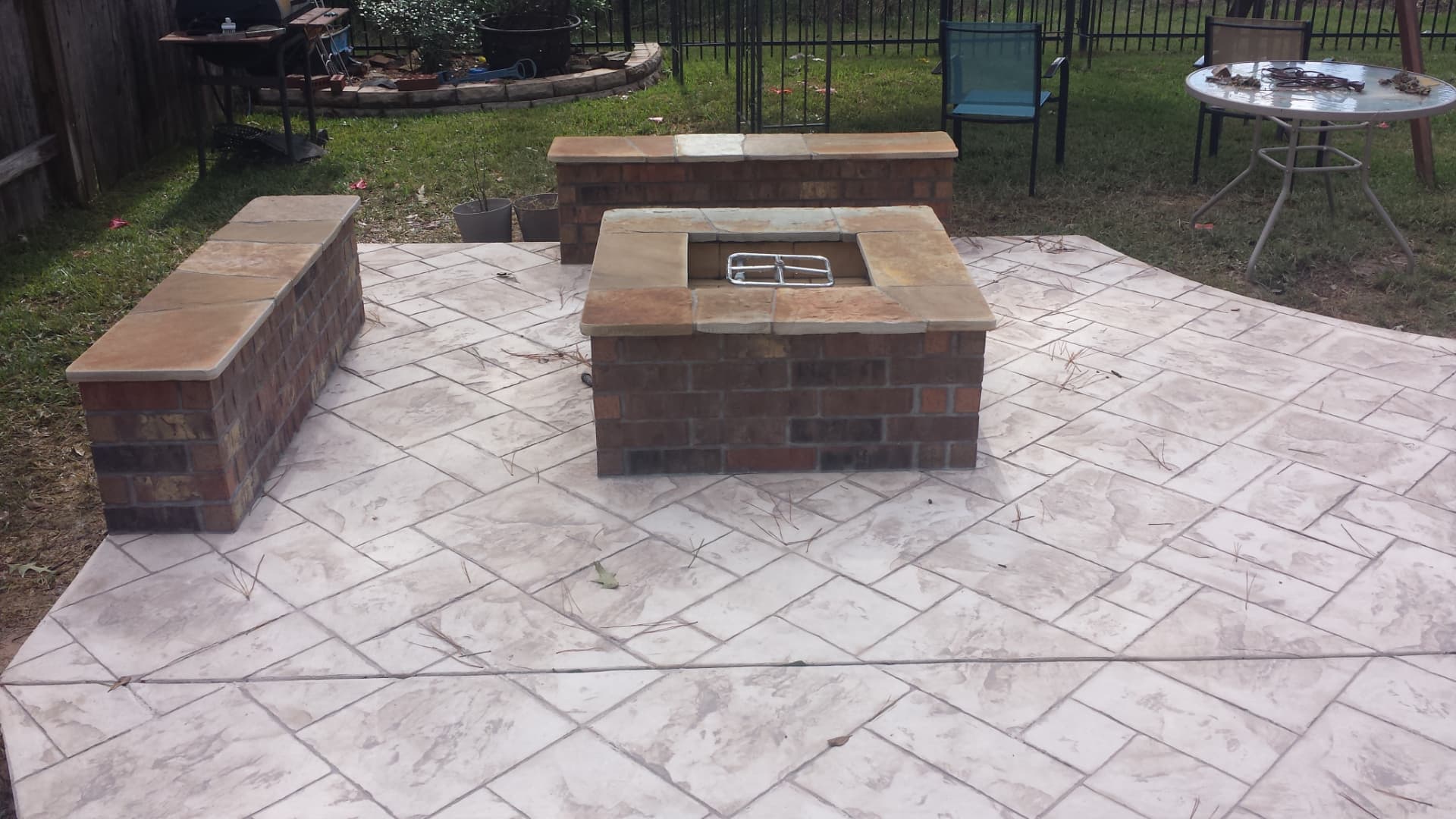 Square brick fire pit with stone caps and seat walls on a stamped concrete patio