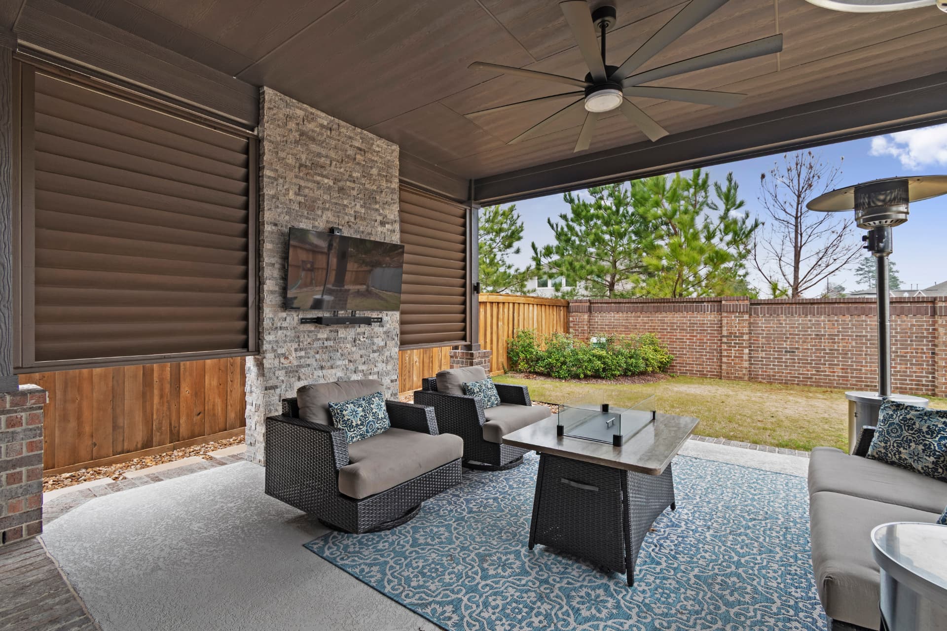 Covered patio with stacked-stone TV wall, fire table and swivel lounge chairs