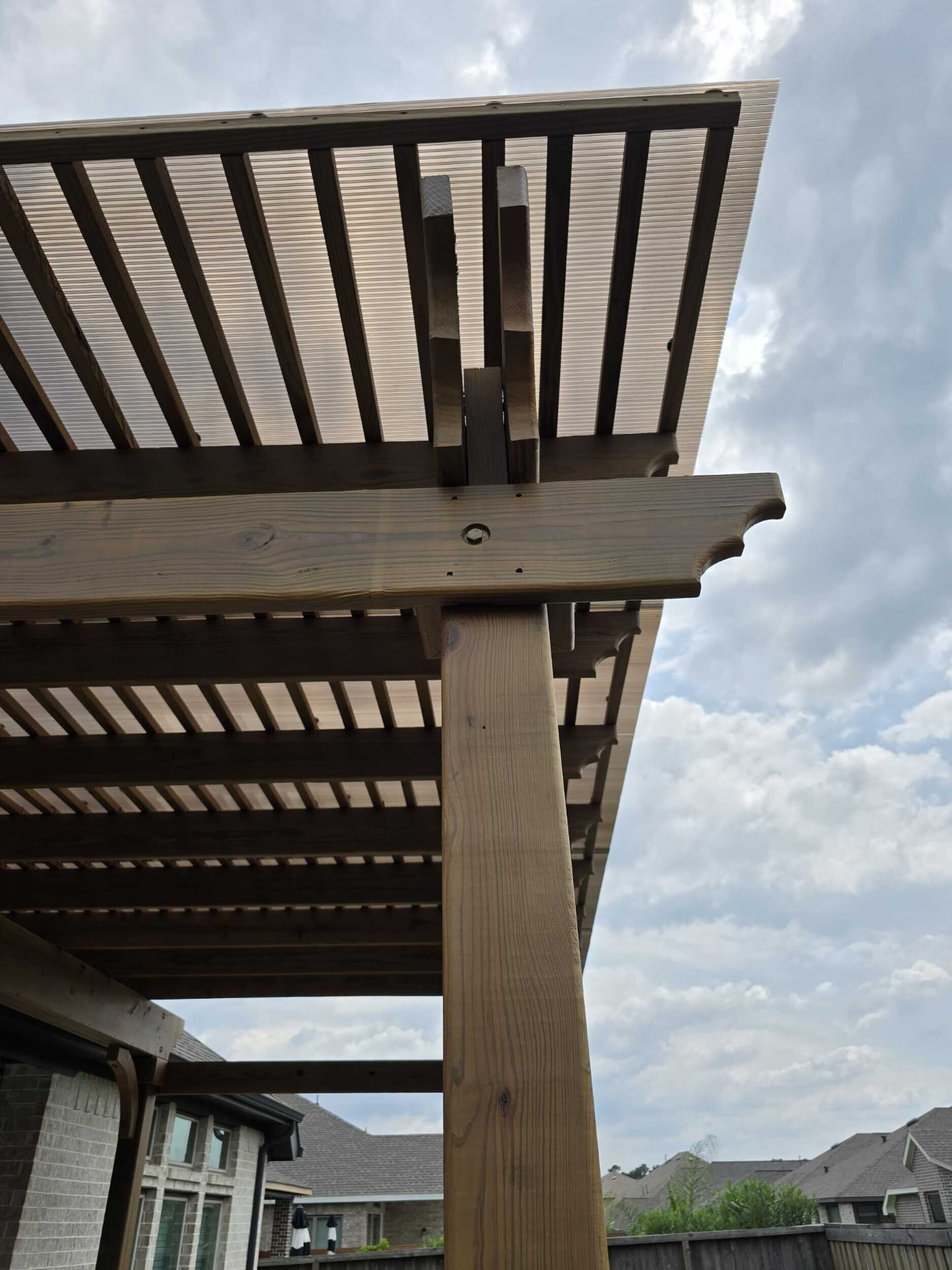 Two-tiered wooden pergola with decorative beams and post caps from below