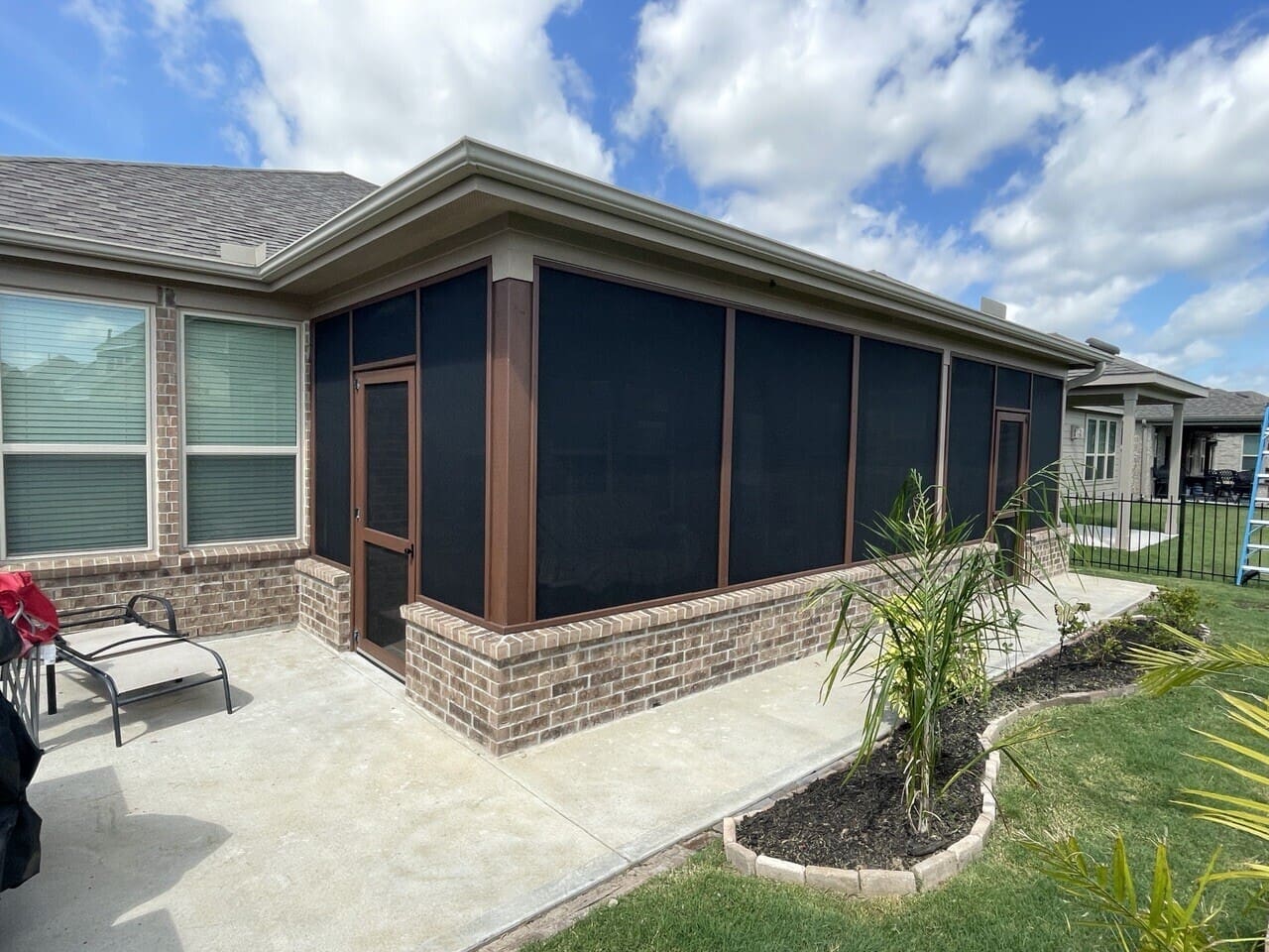 Bronze-frame screened room addition with brick knee wall