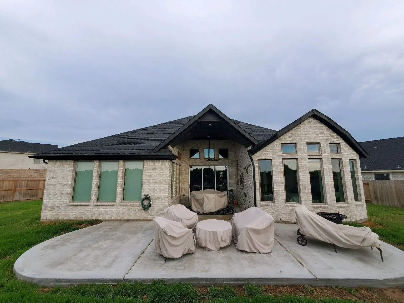 Rear elevation of brick home with new stamped concrete patio ready for outdoor living build