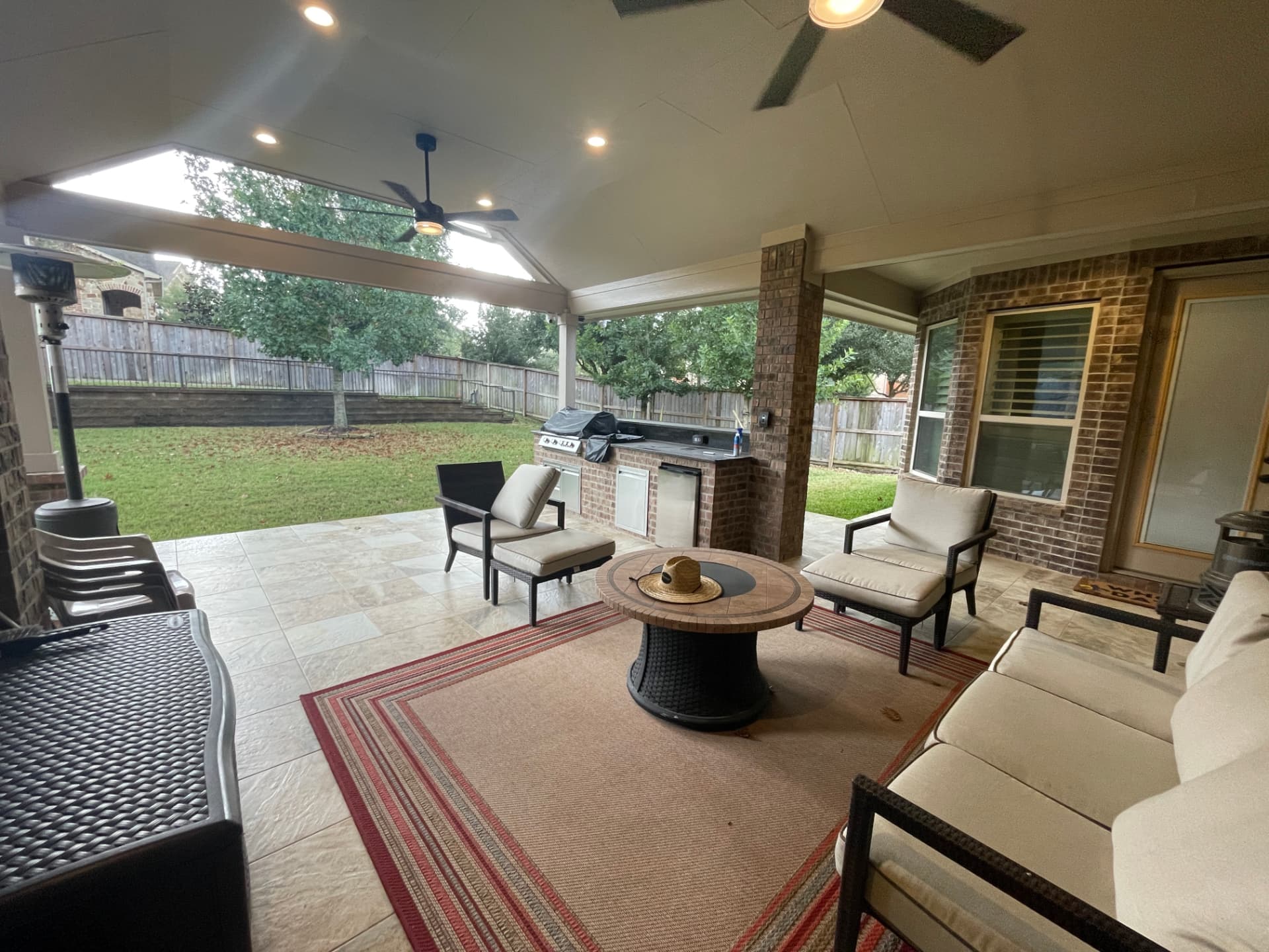 Covered patio with vaulted ceiling, ceiling fans, brick outdoor kitchen and fire pit lounge