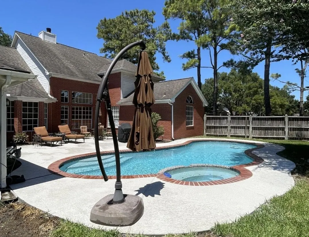 Freeform pool and spa with brick coping and umbrella lounge area