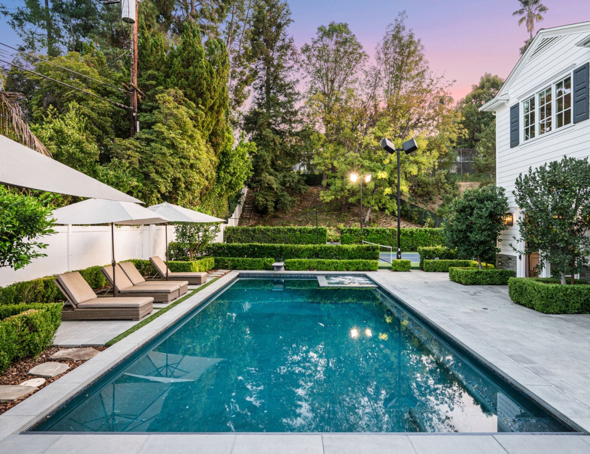 Modern rectangular pool with raised spa, hedge-lined lounge deck and bluestone coping