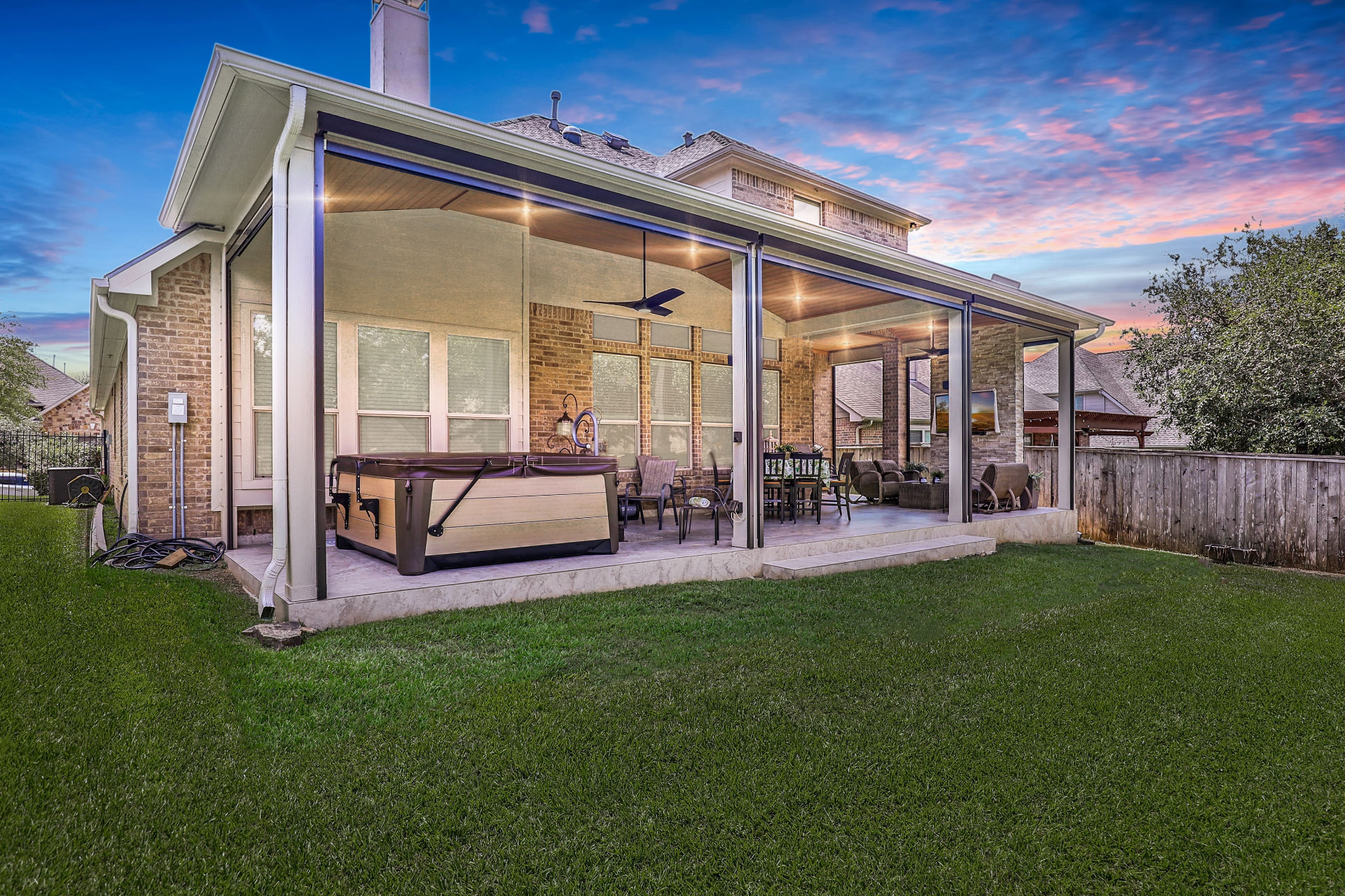 Attached patio cover with motorized privacy screens down at sunset, hot tub and outdoor living room