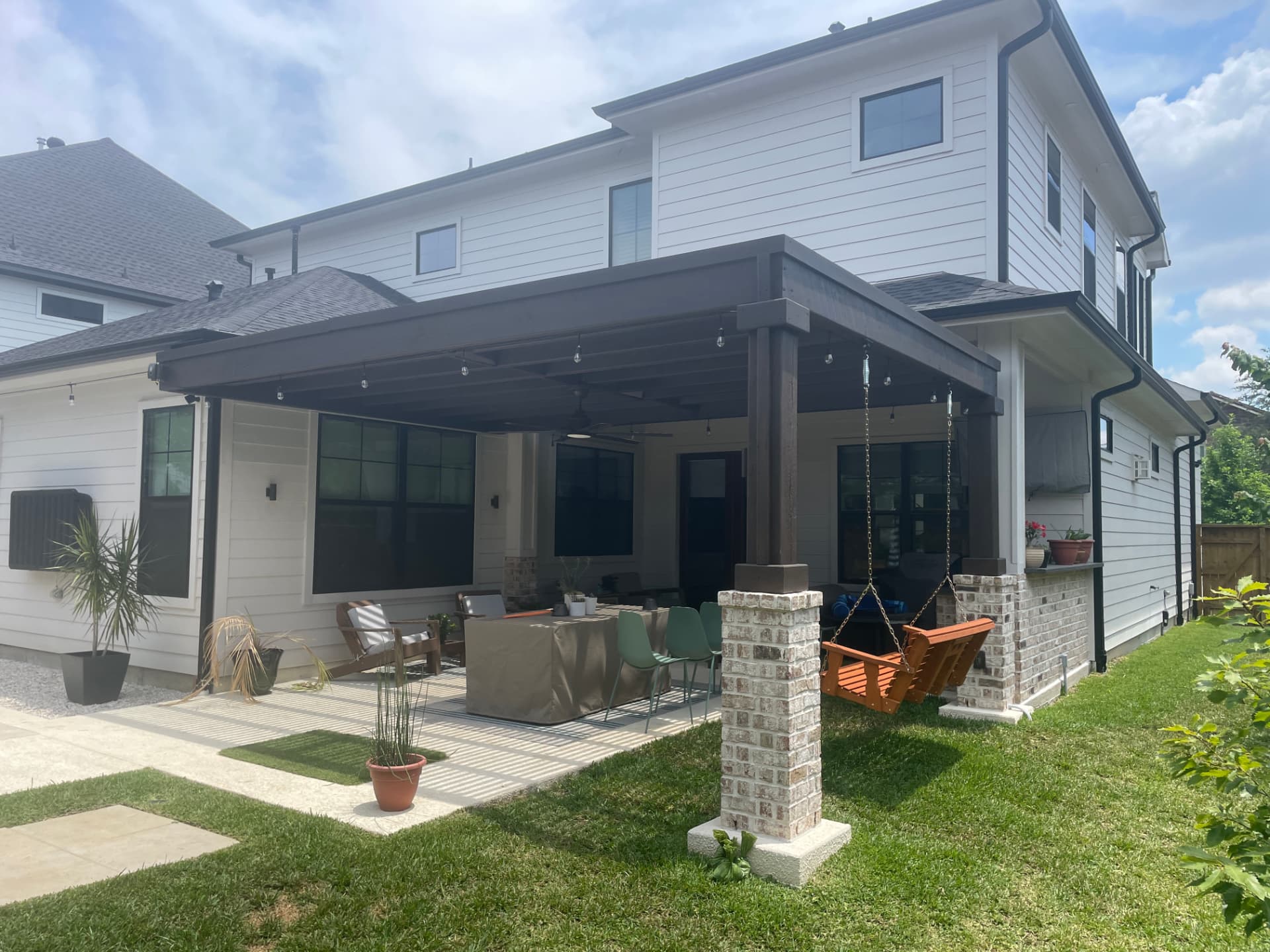 Modern dark-stained pergola with brick columns over covered patio