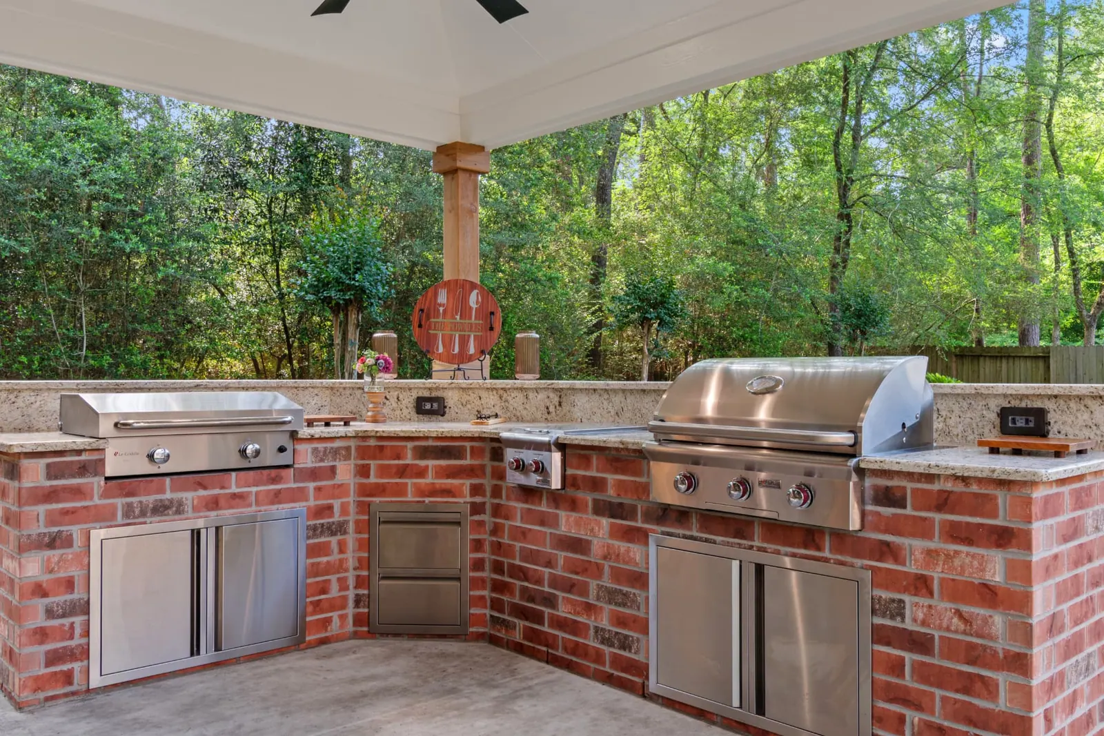L-shaped brick outdoor kitchen with dual grills and granite counters