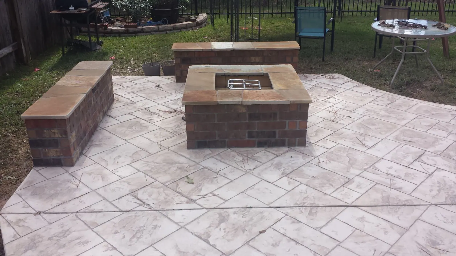 Square brick fire pit with stone caps and seat walls on a stamped concrete patio