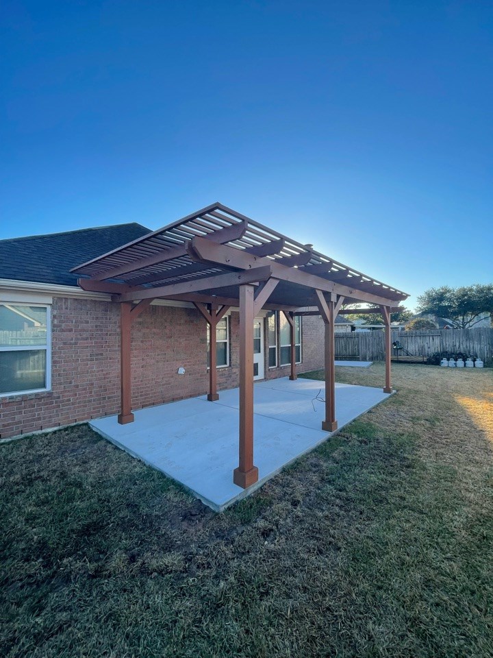 Freestanding wooden pergola over concrete patio in backyard