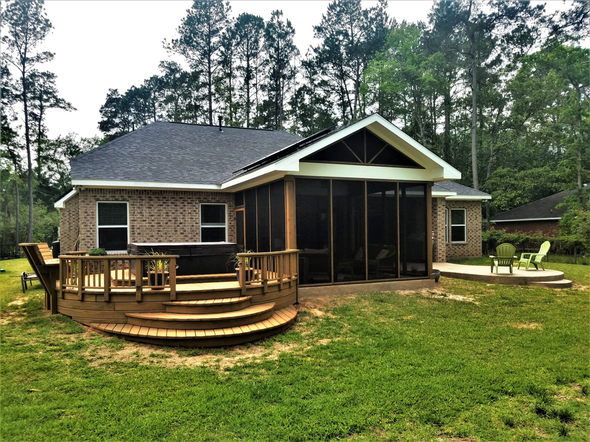 Gabled screened porch with adjoining wood deck and hot tub