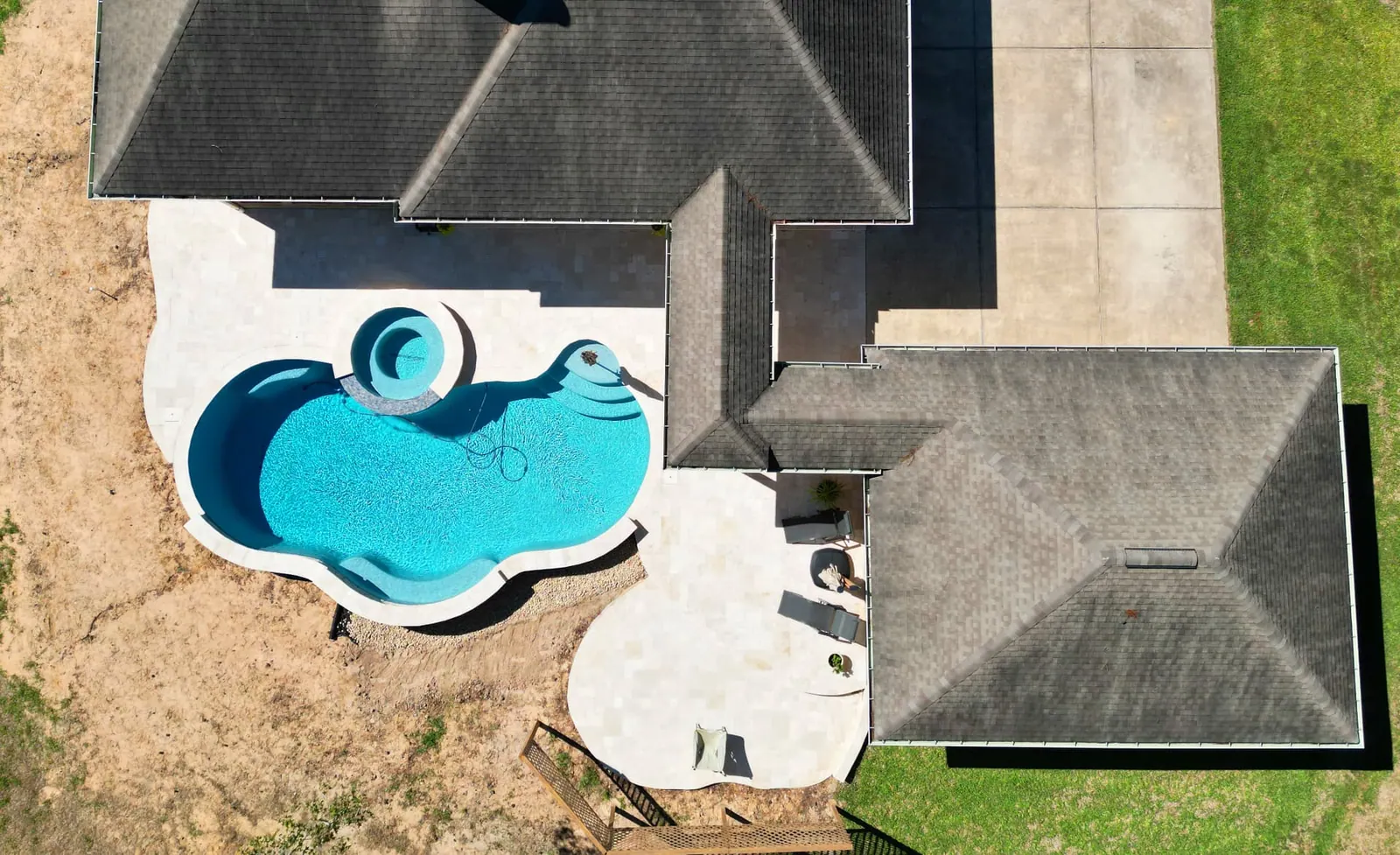 Aerial view of freeform swimming pool with raised spa and travertine decking